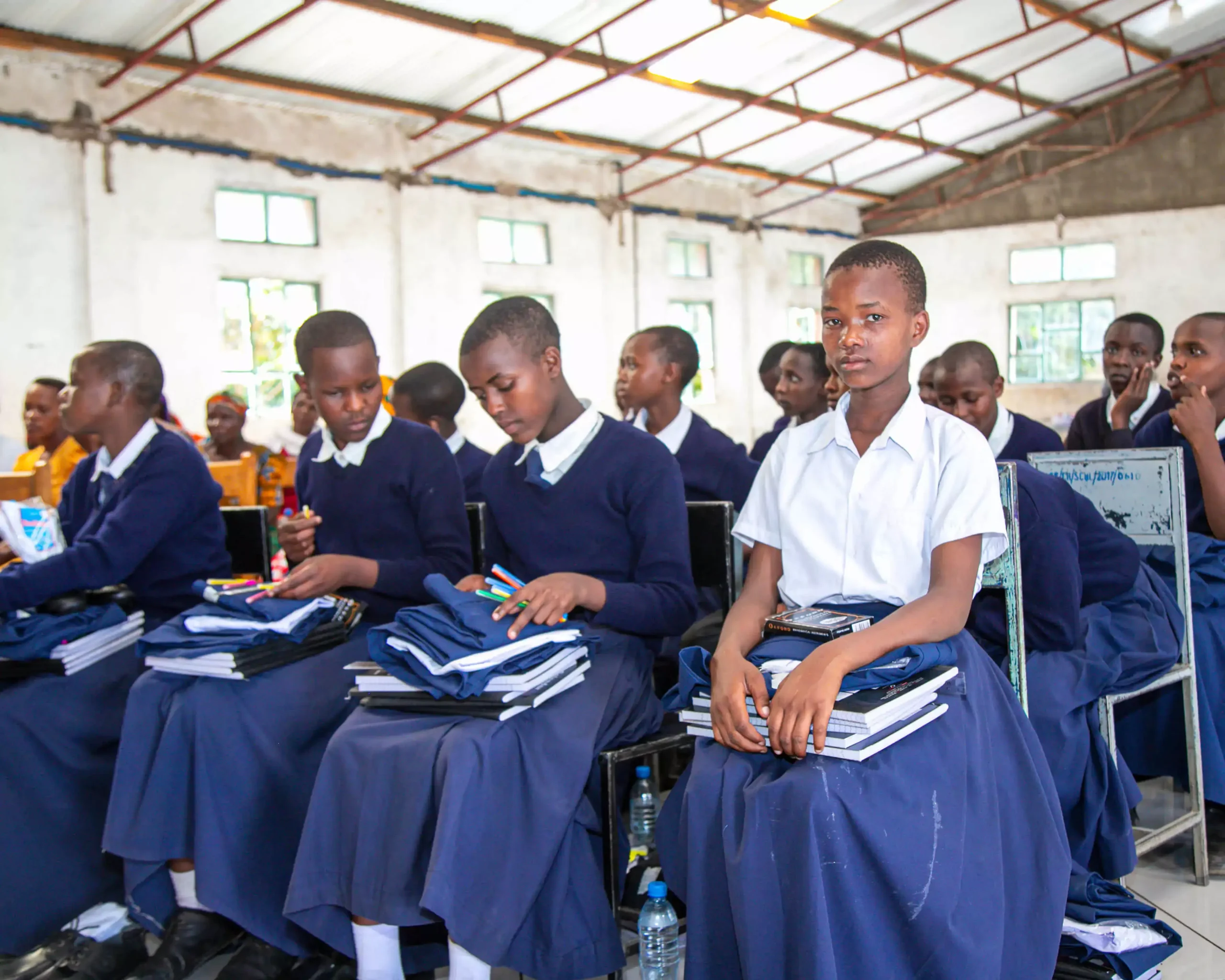 students sitting in classroom holding their new textbooks and school supplies