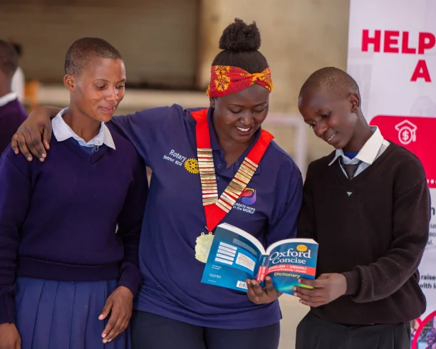 A staff member from a partner institution interacting with two students.