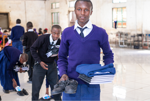 young students holding his new school uniform, shoes and supplies