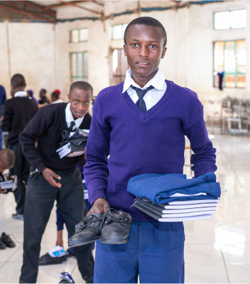 young students holding his new school uniform, shoes and supplies