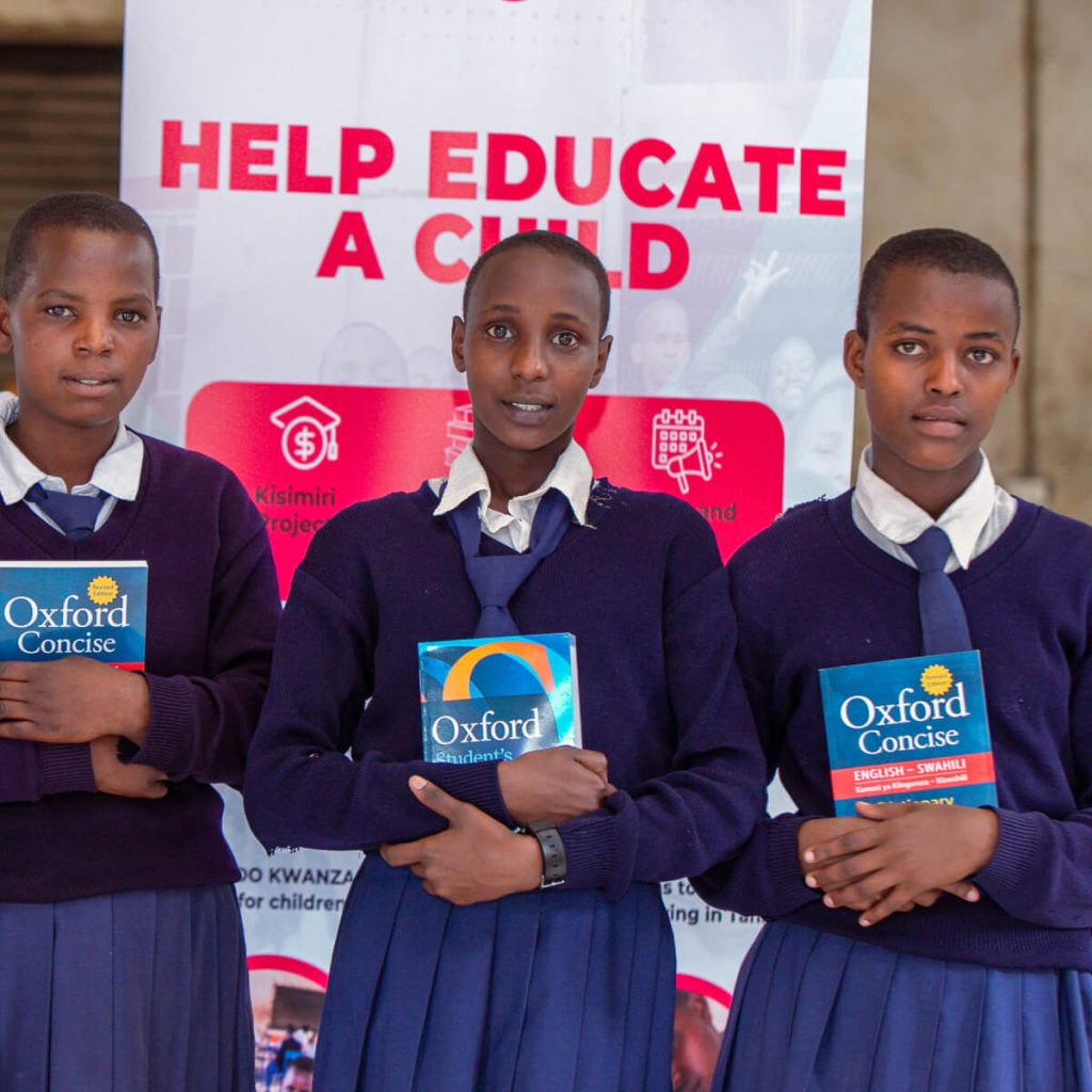 Four young girls wearing blue school uniform holding their new textbooks