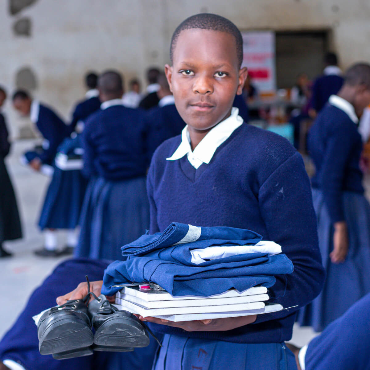 young students holding her new school uniform and supplies