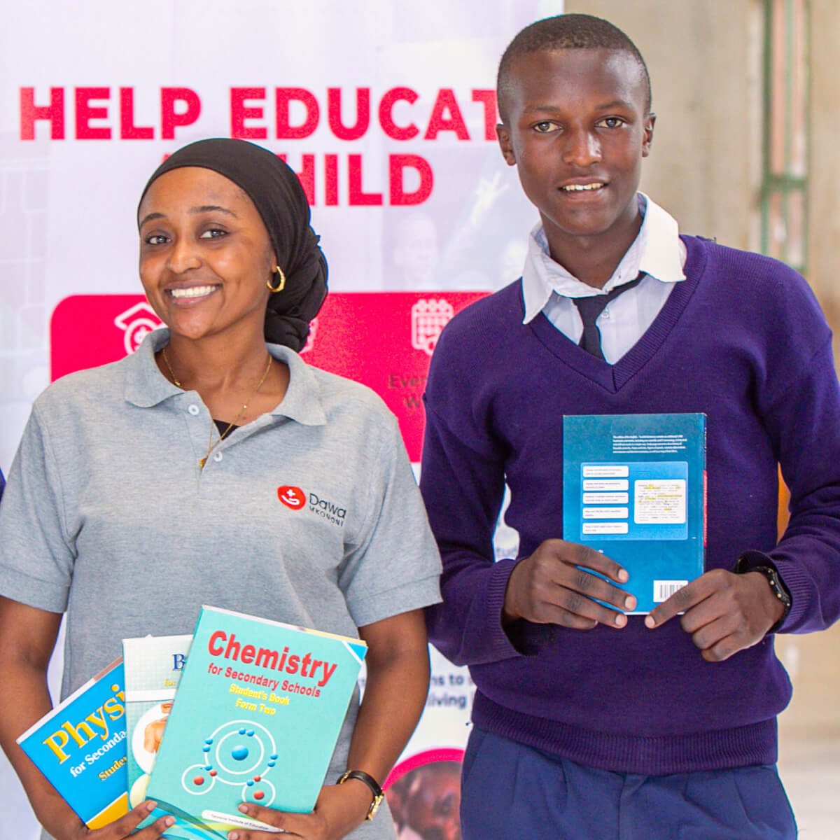 A staff member from a partner institution and students holding donated text books.